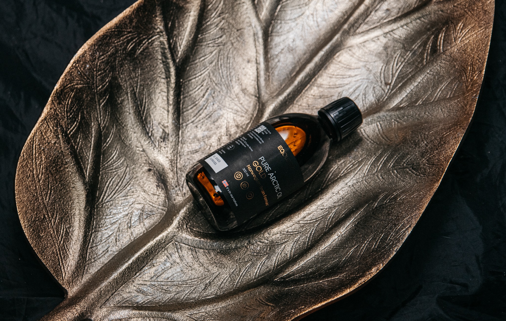 Fotografia produktowa — butelka Pure Arctic Oil na złotej tacy — Fotogłos